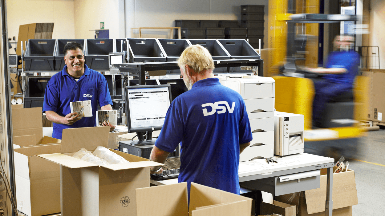 Tre DSV-medarbeidere pakker og registrerer varer.